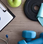 Sports medical technician table with notepad and stethoscope with sports equipment around. Top view.